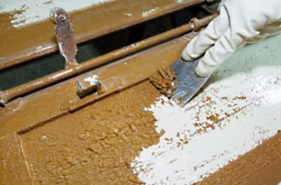 Using caustic paint stripper on an old cabinet door.