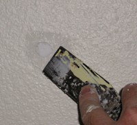 Spackling a minor dent in drywall wall.