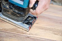 Using a sander to remove varnish from wood.