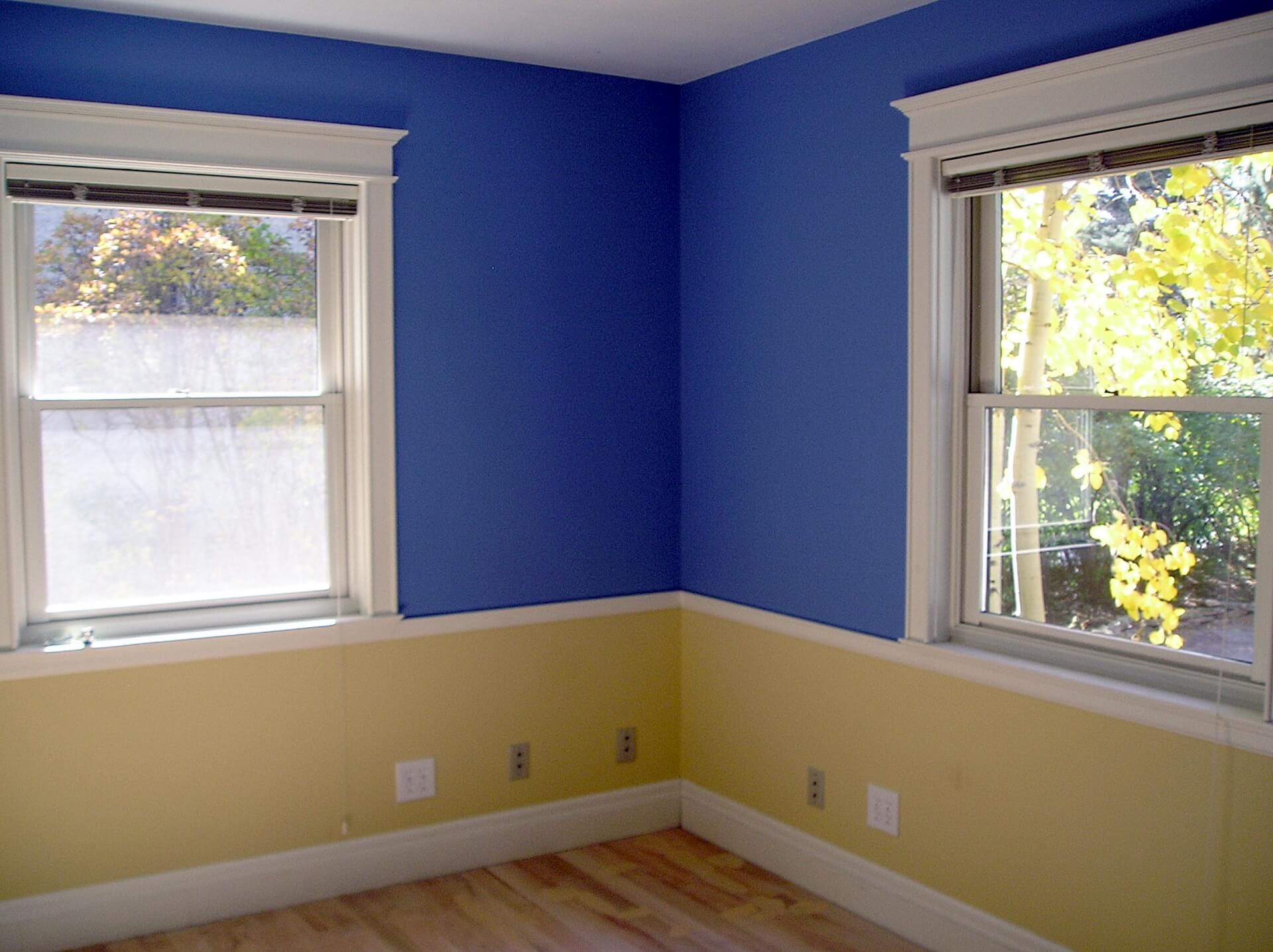 Dining room with a split paint color scheme. Blue on top and yellow below with chair rail trim.