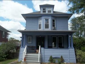 Freshly painted older home with blueish gray siding and white trim.