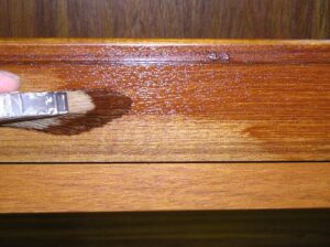 Applying wood stain using a brush to white oak.