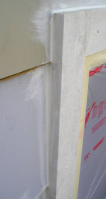 Wood trim and siding caulked next to a wood window.