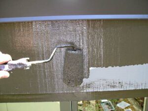 Using a roller to paint a wide fascia board.