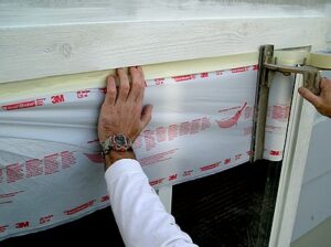 Applying masking film to a window frame.