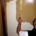 Using a paint roller to paint a steel door.