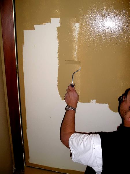 Using a paint roller to paint a steel door.