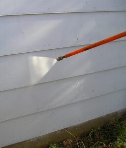 Washing painted siding with a pressure washer.