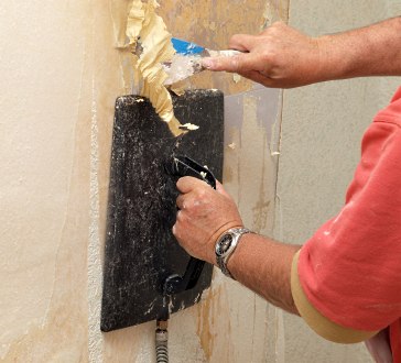 Using a wallpaper steamer to strip wallpaper.