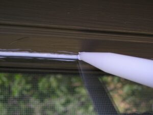 Using clear caulk to seal the glass to the frame of an exterior wood window.