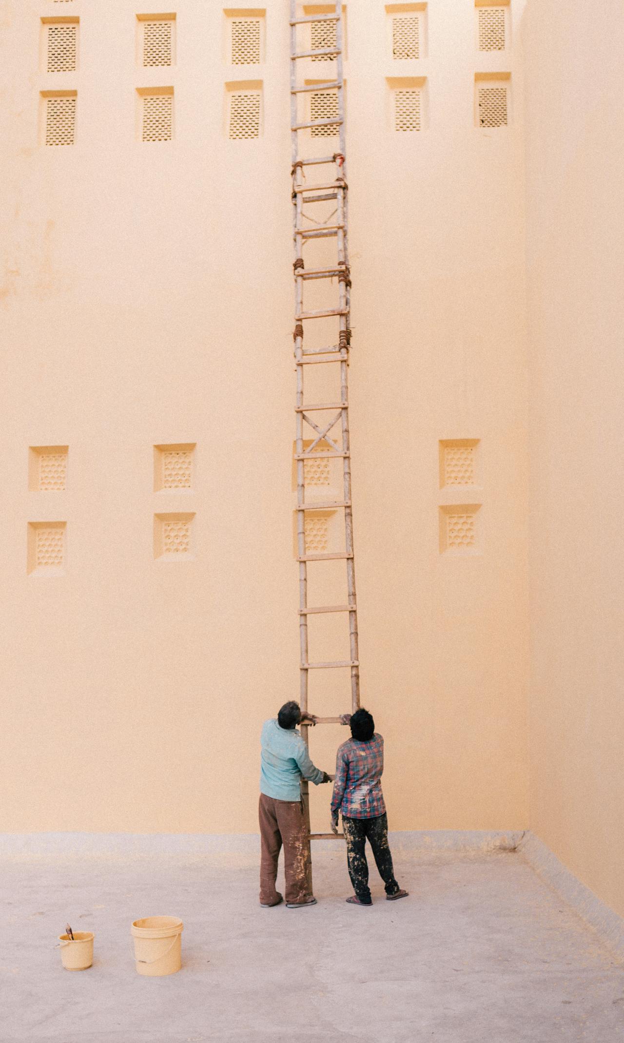 Two men holding a very dangerous extension ladder.