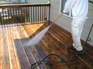 Washing a wood deck with a power washer.