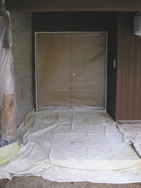 A homes entry fully masked with drop cloths and plastic film.