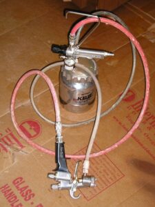 A Cap Spray remote paint pot and attached HVLP paint gun.