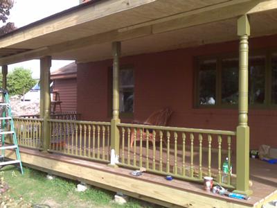 A covered front porch with painted columns and handrail.