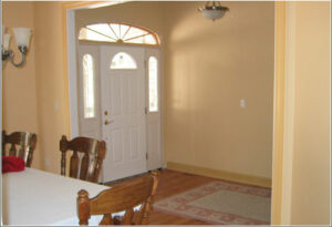 A foyer with light yellow walls and bright with trim and front door.