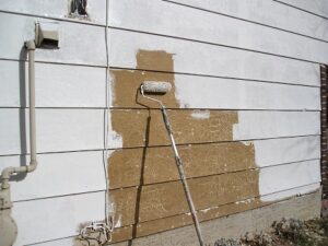 Applying primer to fully prepped smooth masonite siding with a paint roller.