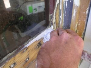 Priming the wood sash of an exterior window.