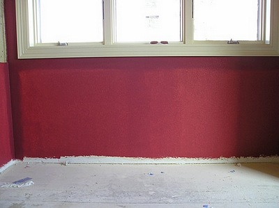 A coat of bright red paint on a wall showing the cut-in and white background.