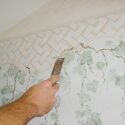 Removing a wallpaper boarder by scraping first then stripping.