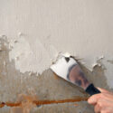 Removing painted wallpaper with a broad putty knife.