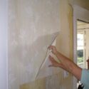 A person stripping the backing paper left on the wall after stripping wallpaper.