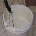 A professional paint roller set-up, 5 gallon bucket with roller grid and paint roller.