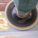 Using a disc sander to sand a wood window sill.