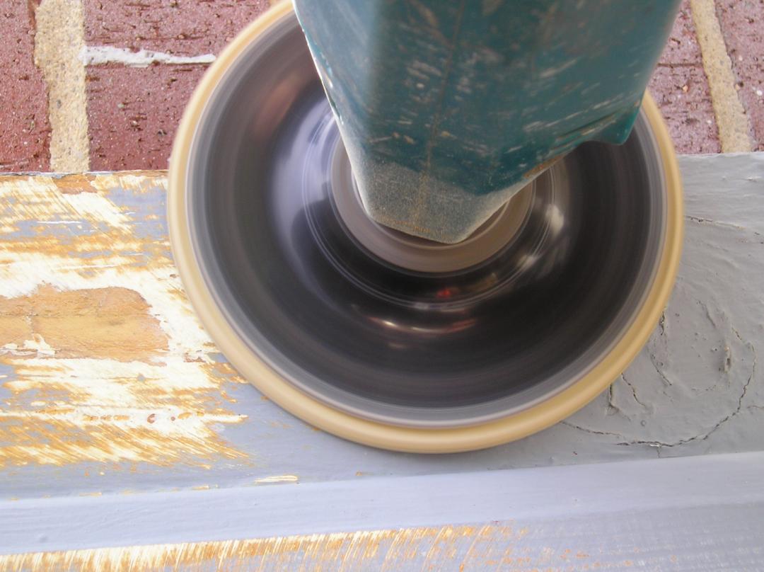 Using a disc sander to sand a wood window sill.