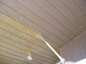 Applying an oil based exterior wood stain to T1-11 siding with an airless sprayer.