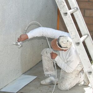 Painter spray painting stucco.