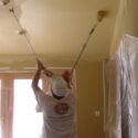 Spraying and then backrolling a room ceiling.