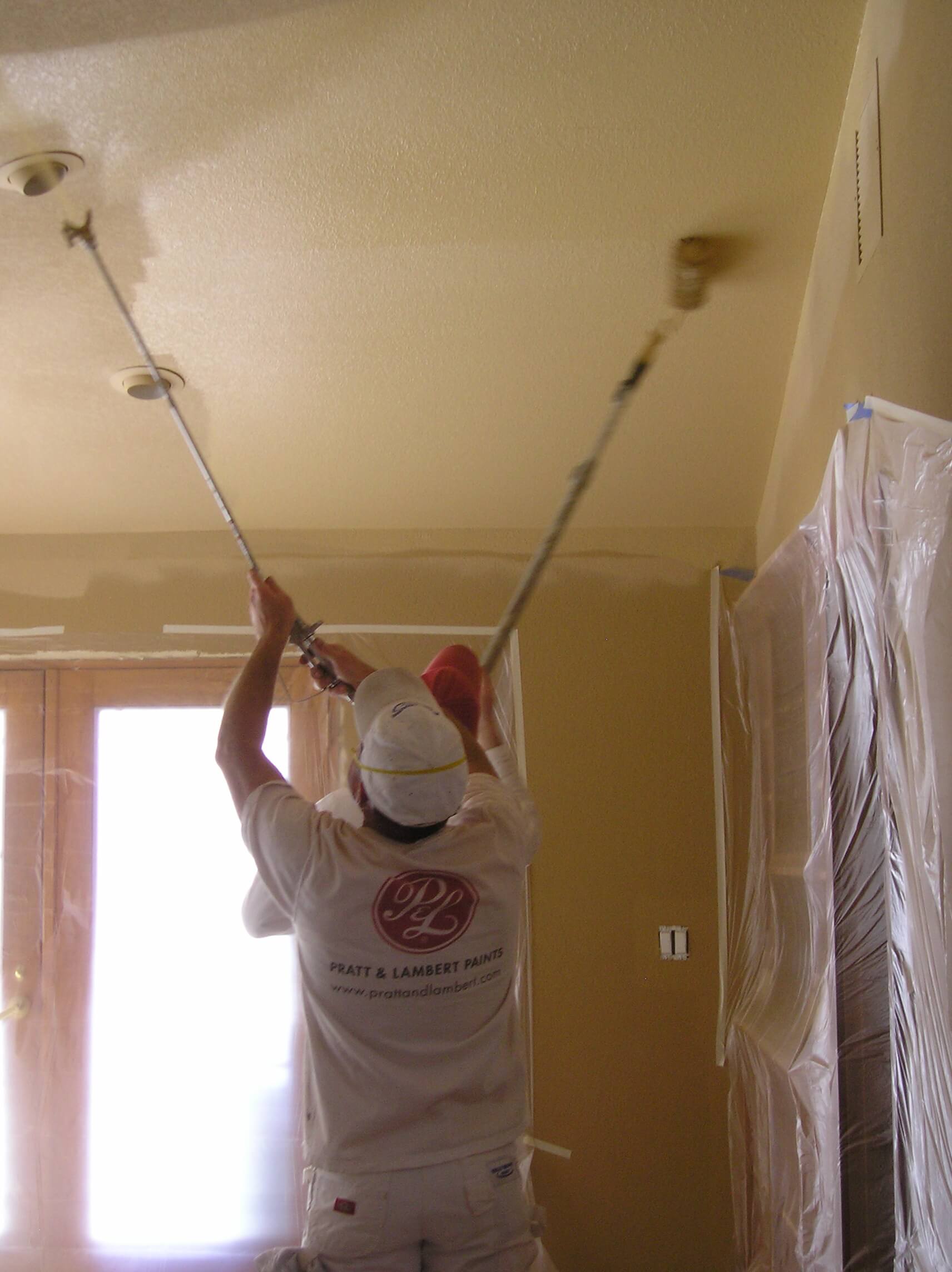 Spraying and then backrolling a room ceiling.