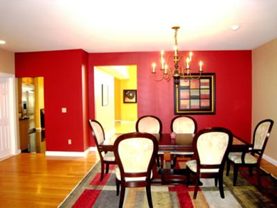 A dining area painted with a red wall, hardwood floor and white ceiling and trim.