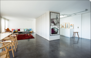 A room with white walls and ceiling with a dark concrete floor.