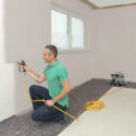 A man applying paint with a Wagner paint sprayer.