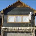 House painter spraying the siding with stain.