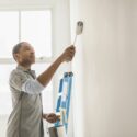 A homeowner painting a wall with a paint roller.