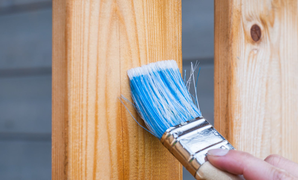 Sealing a wood fence using a brush and clear sealer.