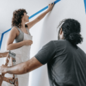 A couple preparing a room for painting by taping off the walls.