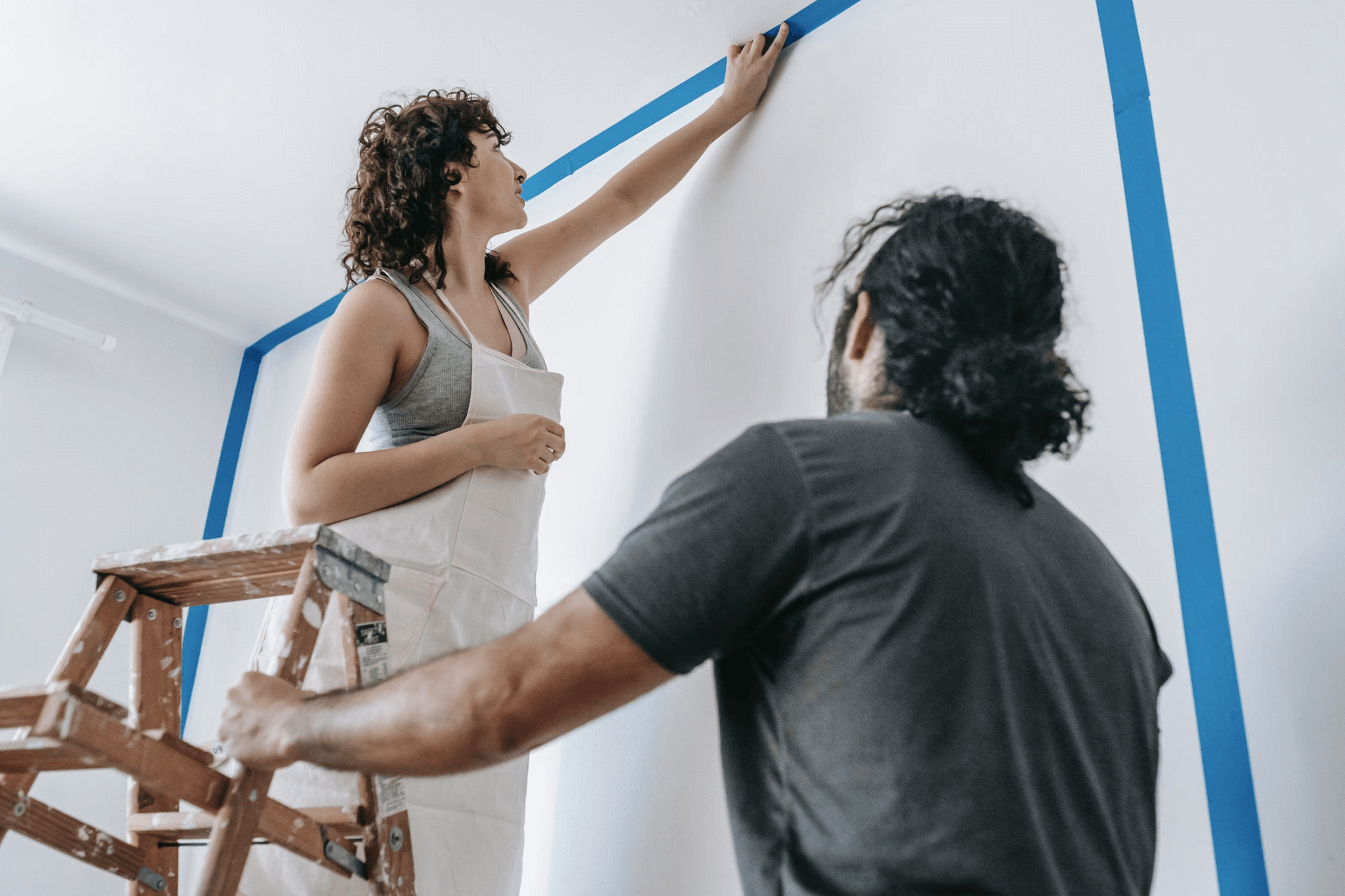 A couple preparing a room for painting by taping off the walls.