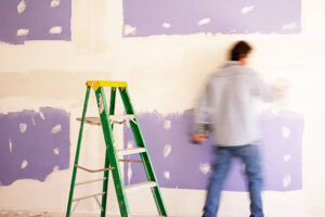 Sheetrocker spreading mud on seams of new sheetrock wall. He is in motion.
